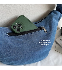 Detailed view of back zipper pocket on blue denim crossbody bag for secure phone storage