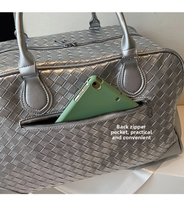 Detail of silver woven travel bag showing a functional rear zipper pocket for a tablet