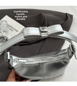 Detail of silver metallic handbag with bow handle and sturdy metal snap closure