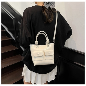 Detail of cream crocodile embossed handbag featuring decorative front flap pockets