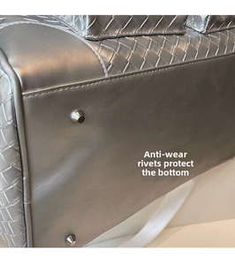 Detail of woven texture weekend bag featuring protective metal rivets on the bottom