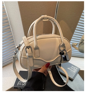 Detail of cream white mini bowling bag featuring silver lock and key charm detail