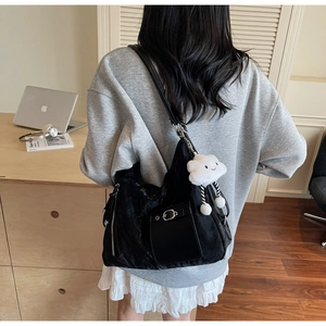 Detail of black tote bag featuring textured fabric and a cute white plush cloud charm