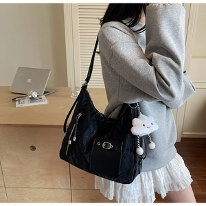 Close-up of black pleated nylon tote bag with silver buckle and plush cloud charm