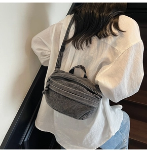 Detail of vintage grey denim crossbody bag showing washed texture and zipper pockets