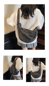 Detail of dark grey washed denim hobo bag featuring adjustable wide strap and crescent shape