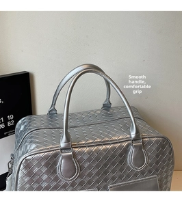 Macro detail of silver woven texture and reinforced handle stitching on travel bag