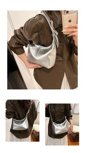 Detail of silver metallic hobo bag with a knotted shoulder strap and zipper closure