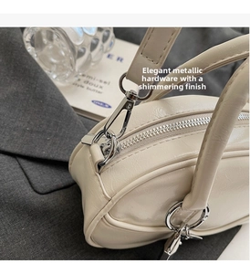 Detail of a creamy white leather bowling bag with polished silver hardware and zipper