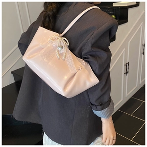 Détail du sac cabas rose clair avec nœud en perles, dentelle et pendentif cœur