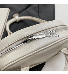 Detail of a smooth silver zipper on a beige retro bowling bag with textured leather