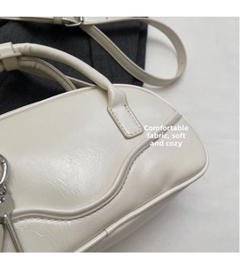 Close-up of cream bowling bag showing soft PU leather texture and metal key pendant