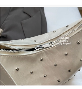 Detail of smooth silver metal zipper and silver rivets on a beige leather handbag