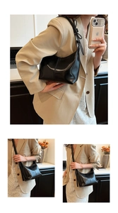 Detail of black semi-circle crossbody bag with adjustable bow shoulder strap and glossy finish