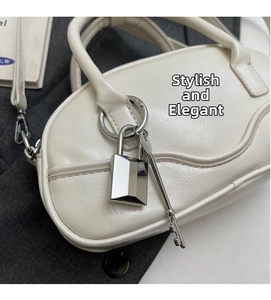 Detail view of a white bowling bag with metallic lock, key charm and detachable strap