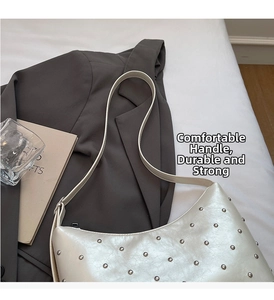 Detail of cream-colored rivet shoulder bag with textured leather on a grey blazer