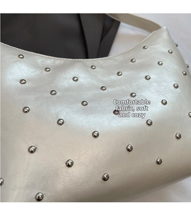 Close-up of creamy white lychee grain leather texture and silver rivet details on bag