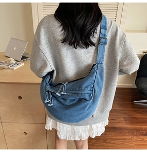 Detail of blue denim crescent bag featuring large capacity and tassel zipper detail