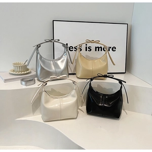 Hobo bags in four colors with bow details displayed on minimalist white stairs