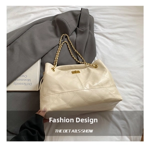 Close-up of beige quilted leather handbag with gold chain strap and metal lock detail