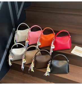 Détail de sacs seaux en huit coloris avec cuir texturé et pendentifs à pompons arc-en-ciel