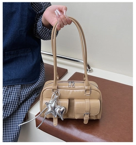 Close-up of crocodile-embossed pockets and silver heart charms on a khaki bowling bag