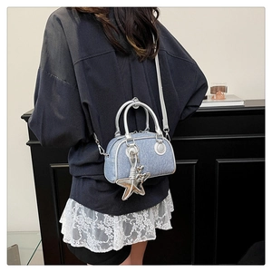 Detail of blue denim crossbody bag with silver star charm and metallic zipper