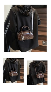 Detail of dark brown vintage bowling bag with shiny leather texture and key pendant