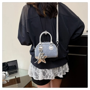 Mini denim bowling bag with silver ring handles and star charm shown on a model