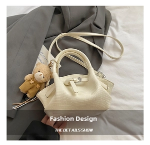 Detail of cream crocodile pattern bucket bag with a cute brown bear plush charm