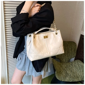 Detail of white quilted handbag with golden chain strap and vintage square twist lock