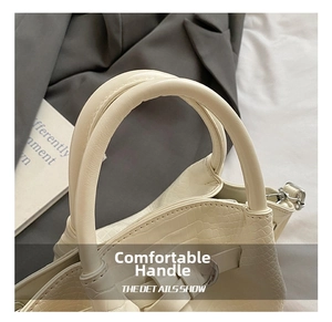 Detail of cream white bucket bag featuring elegant crocodile pattern and dual round handles
