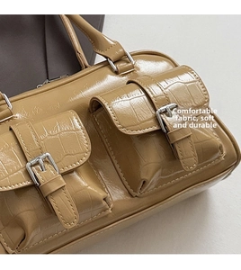 Detail of caramel crocodile pattern handbag with dual front pockets and silver buckles