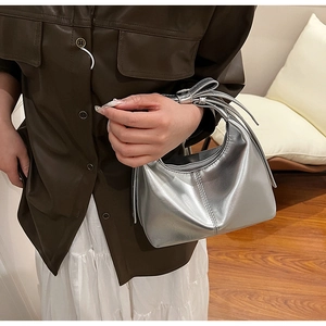 Detail of silver metallic hobo bag featuring a decorative bow knot on the handle strap