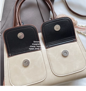 Detail of beige tote bag showing black contrast pocket with magnetic buckle closure