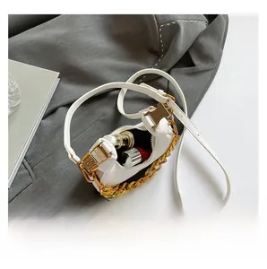 Detail showing internal capacity of cream crescent bag with lipstick and perfume bottles