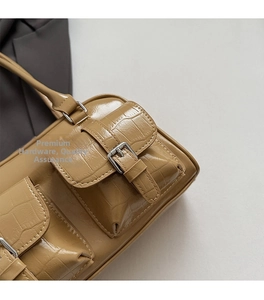Detail of tan embossed leather handbag showing silver buckles and flap pockets