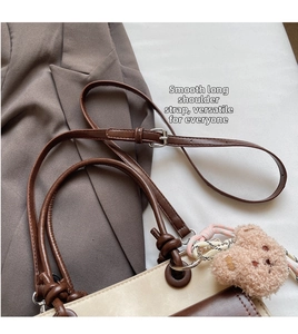Detail of color-block tote bag featuring adjustable strap and plush bear charm