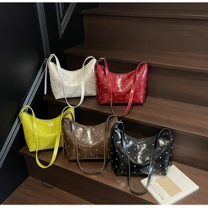 Detail showing five colors of crescent bags with silver rivets on glossy faux leather