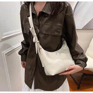 Close-up of off-white hobo bag with a stylish bow decoration on the shoulder strap
