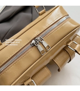 Detail of smooth silver double zippers and khaki crocodile texture on bowling bag
