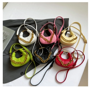 Flat lay of mini crescent bags in multiple colors featuring gold chains and leather textures