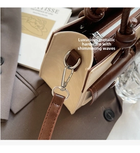 Detail of two-tone bucket bag with silver metal buckle and premium leather stitching