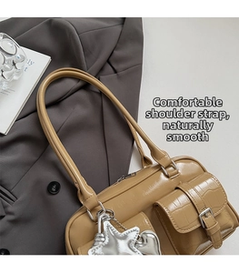 Close-up of khaki crocodile-textured shoulder bag with silver star and heart charms