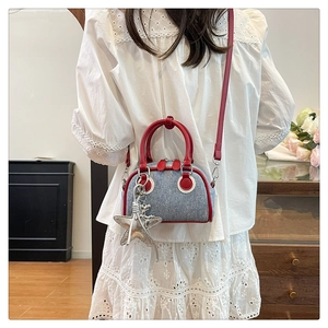Détail du mini sac bowling en denim avec garniture en cuir rouge et breloque étoile de mer