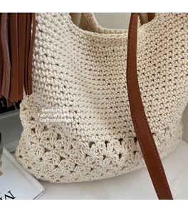 Detail of the woven floral texture and brown leather strap on the cream crochet tote bag
