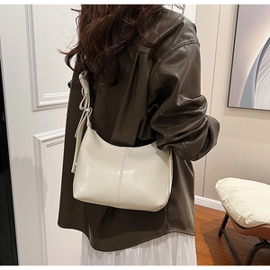 Détail du sac seau hobo crème avec coutures verticales et nœud décoratif à l'épaule