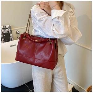 Detail of red quilted leather tote bag with elegant metal and leather chain strap