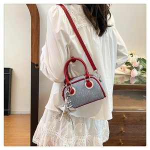 Detail of blue denim Boston bag with red leather trim and a silver star pendant