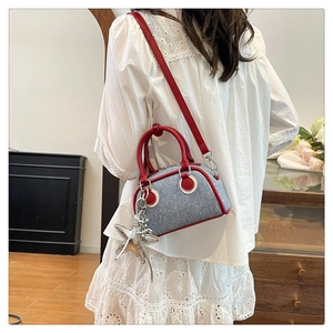 Detail of blue denim mini bag with red leather trim and a silver star pendant decoration